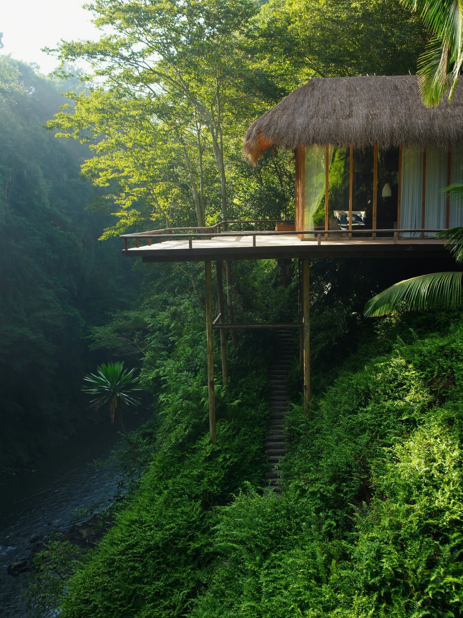 A teak and glass pavilion cantilevered over a green ravine near Ubud.